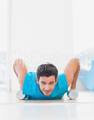 Man doing push ups with dumbbells in fitness studio