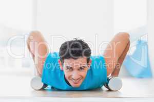 Man doing push ups with dumbbells in fitness studio