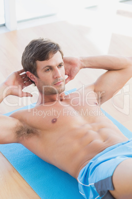 Determined shirtless young man doing sit ups