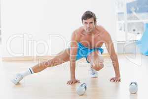 Sporty shirtless man exercising in fitness studio