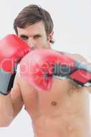 Portrait of a serious young man in red boxing gloves