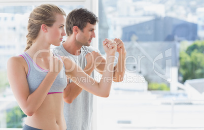 Serious couple standing in boxing stance in fitness studio