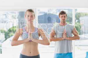 Couple with joined hands and eyes closed in fitness studio