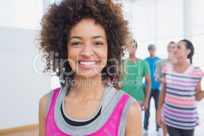 Cheerful instructor with fitness class in background
