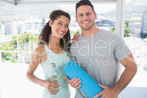 Couple holding water bottle and exercise mat