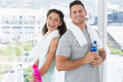 Couple with towels and water bottles at gym