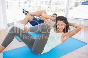 Couple doing sit ups in fitness studio