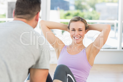 Trainer helping woman doing sit ups