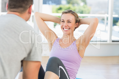 Trainer assisting fit woman in doing sits up