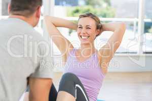 Trainer assisting fit woman in doing sits up