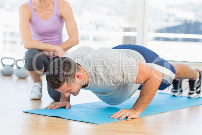 Trainer helping man with push ups
