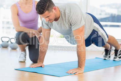 Trainer assisting man with push ups