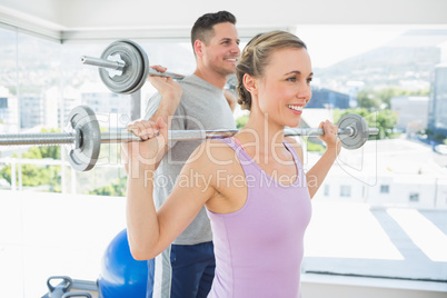 Fit woman and man lifting barbells