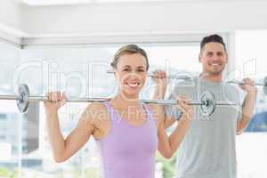 Woman and man lifting barbells at fitness studio