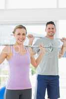 Fit woman and man lifting weights at gym
