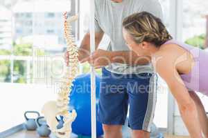 Trainer showing model of spinal cord to woman