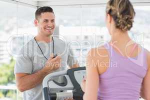 Trainer helping woman on treadmill