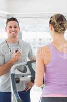 Fitness trainer holding stopwatch with woman exercising