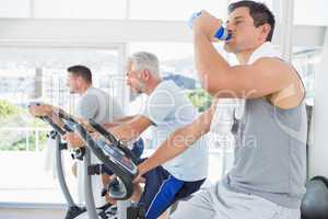Man on exercise bike drinking water