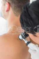 Doctor examining melanoma on back of man