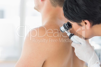 Doctor examining mole on back of man