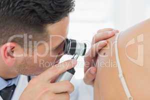 Dermatologist checking mole on woman