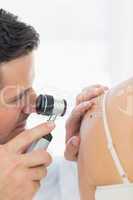 Doctor checking mole on woman