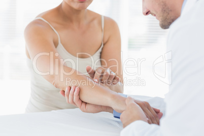 Male physiotherapist examining hand of woman