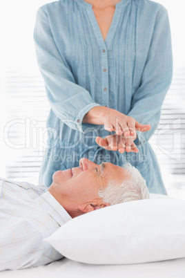 Therapist performing Reiki over forehead of man