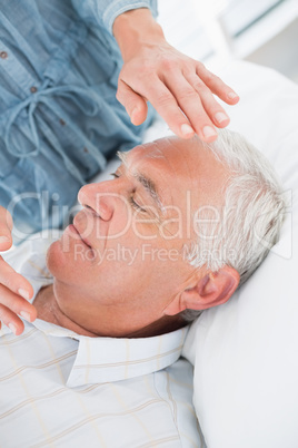 Man receiving Reiki treatment by therapist