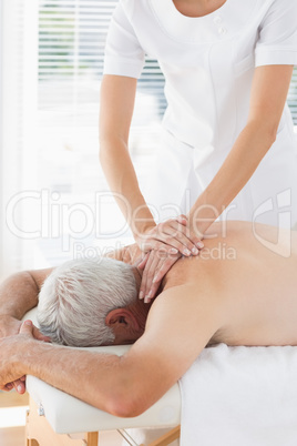 Physiotherapist massaging back of patient