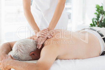 Therapist massaging back of senior patient