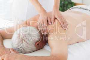 Therapist massaging back of senior man