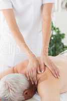 Massage therapist massaging back of senior man