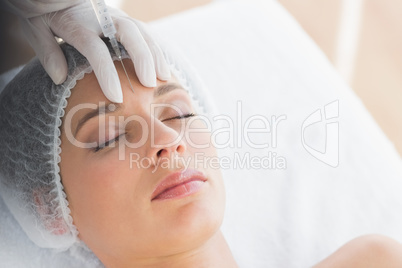 Woman recieving botox injection in forehead