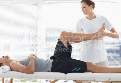 Physiotherapist massaging leg of man