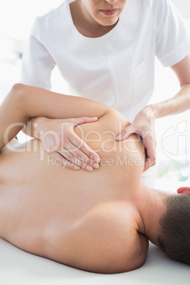 Professional therapist giving shoulder massage to man