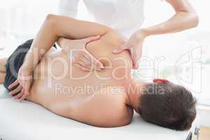 Physiotherapist giving shoulder massage to man
