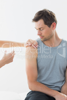 Doctor injecting man on arm in clinic