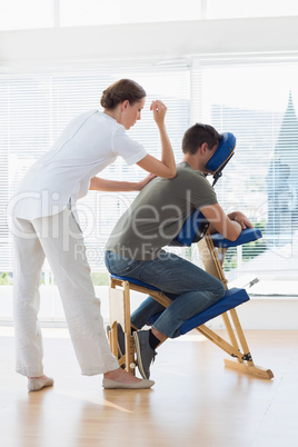 Female therapist giving back massage to man