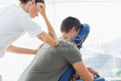 Therapist giving back massage to man