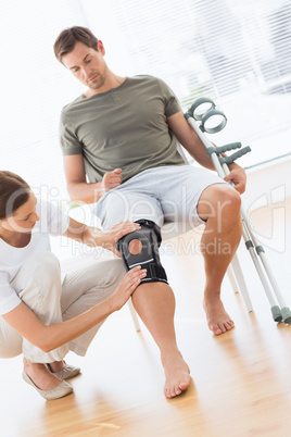 Physiotherapist checking man with crutches