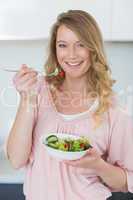 Woman having salad in kitchen