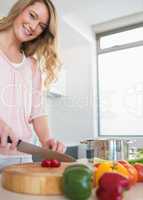 Happy woman chopping vegetables on board