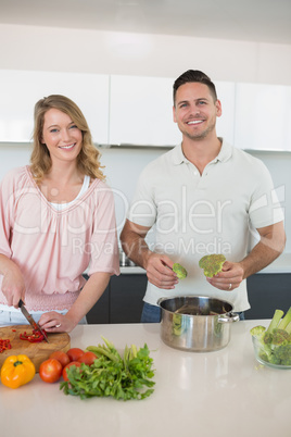 Happy couple preparing food in kitchen