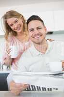 Couple with coffee mugs and newspaper in kitchen