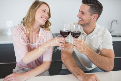 Couple toasting red wine glasses at table