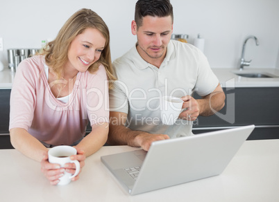 Couple with coffee cups using laptop at table