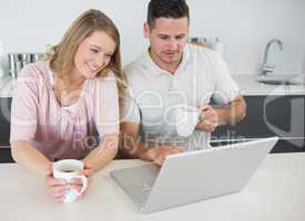 Couple with coffee cups using laptop at table