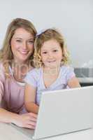 Mother and daughter with laptop at kitchen table